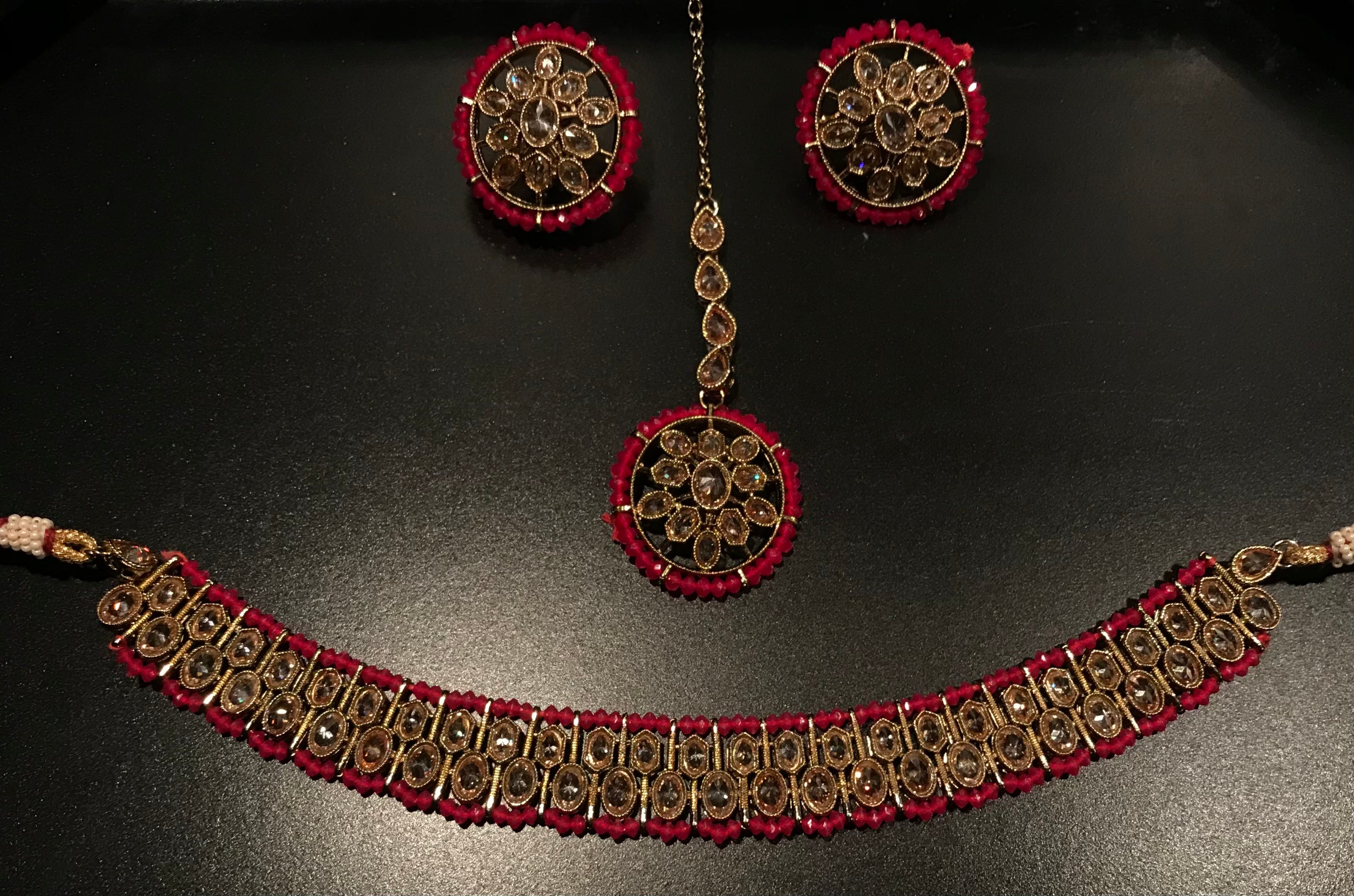 This breathtaking Mehek choker set is so versatile, dainty, exquisite and perfect.  Whether you choose to  wear the set  with a neutral simple ensemble or with a glamorous ensemble, this set will surely shine.    Product Details:  -  Gold-plated base  -Stone tones include: bronze crystals   - Magenta, yellow and white  bead accents  -Comes with earrings, maang tikka & choker ﻿only.   Product dimensions:  Length- 17cm  Width- 2cm