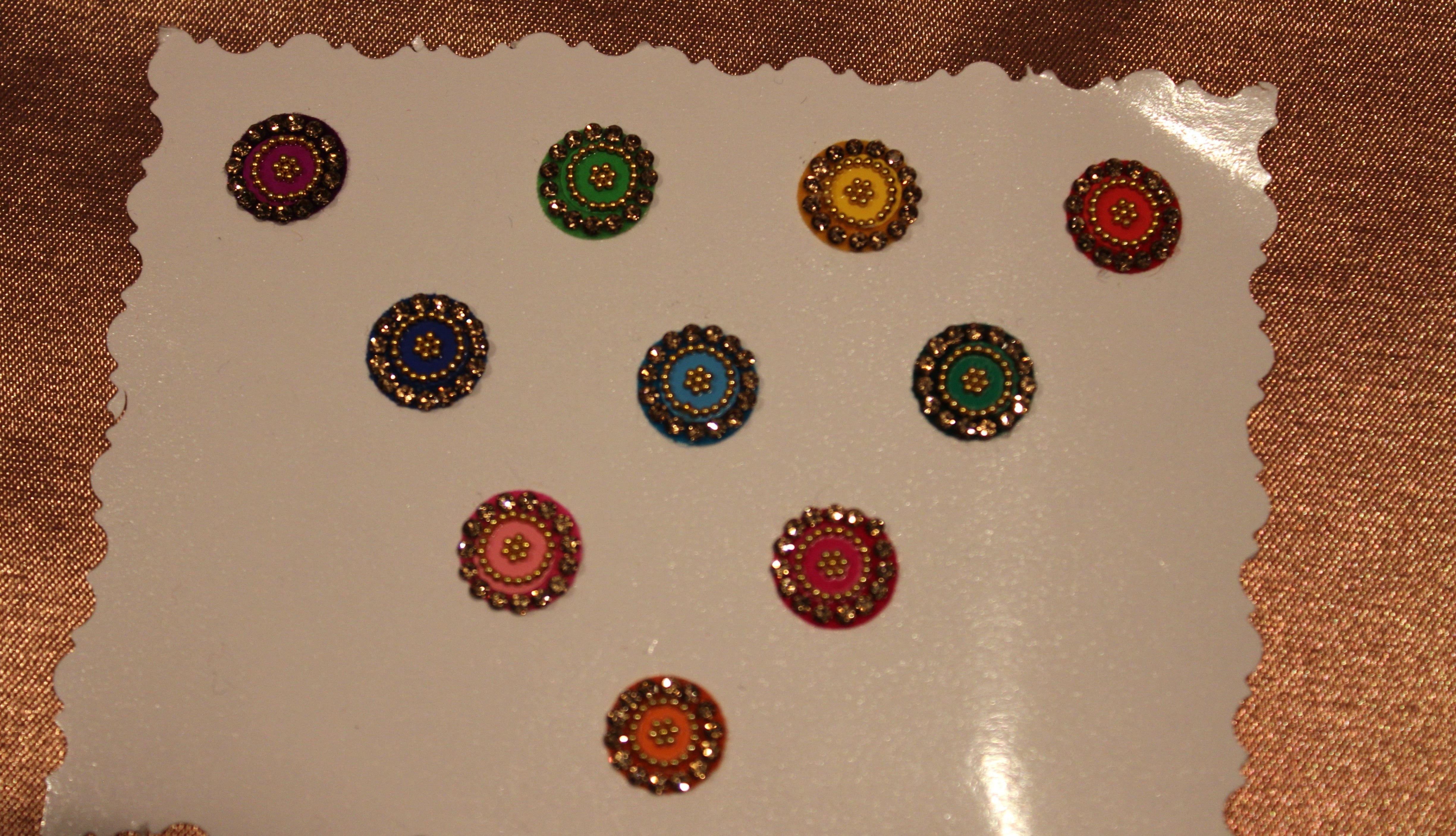 Bindis are coloured dots worn on the centre of a woman's forehead they come in various designs and shapes.   A card of bindis come in different colours and are reusable. To reuse the adhesive after it is worn off, we recommend the use of eyelash glue for application. 